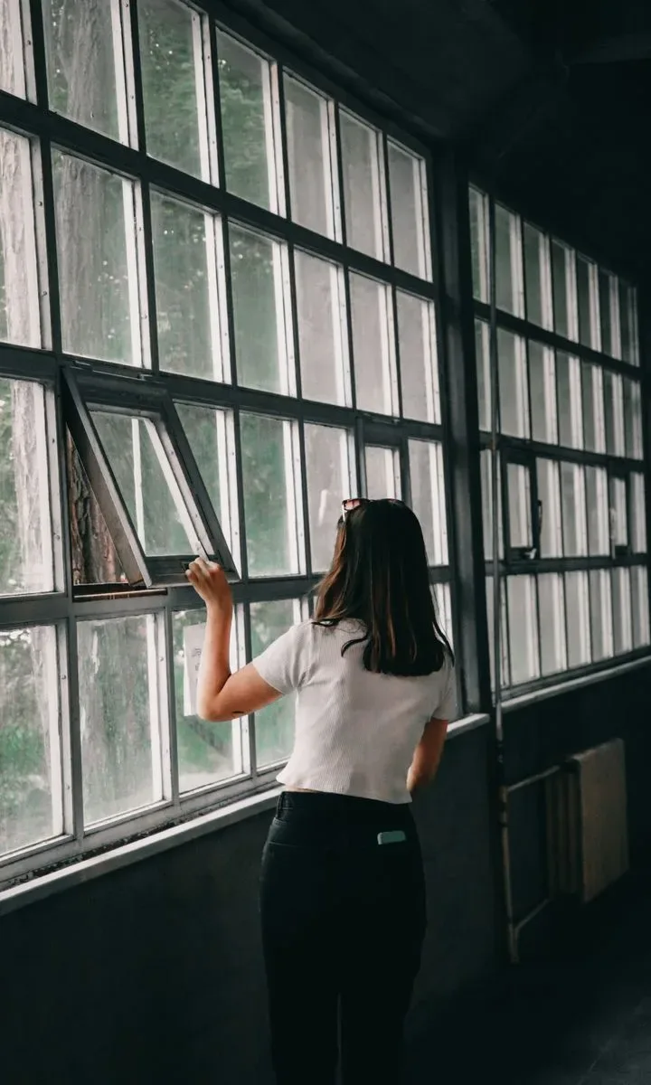Cómo eliminar malos olores del departamento sin gastar en aromatizantes. Una persona abriendo una ventana para ventilar la habitación, mostrando la importancia de la buena ventilación para eliminar olores.