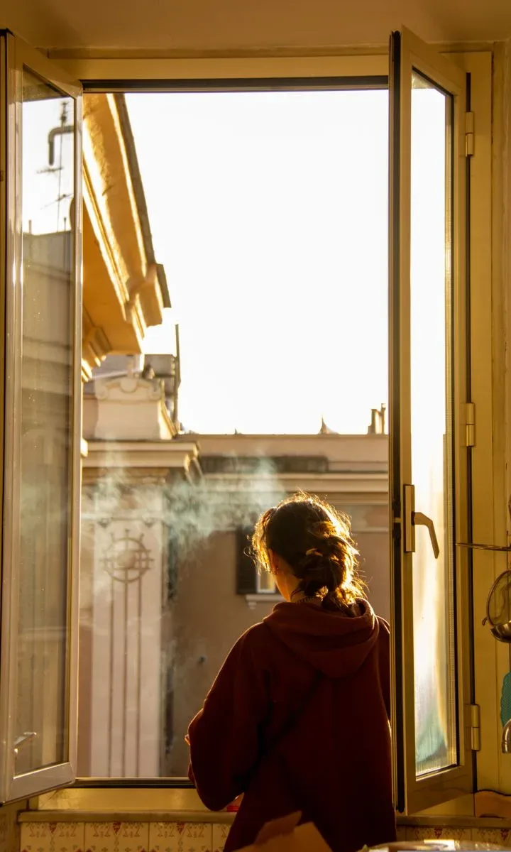 Estos son los mejores trucos caseros para evitar que las ventanas transpiren en invierno Mano abriendo una ventana para ventilar la habitación, ilustrando el truco de ventilar la casa a diario para reducir la condensación.
