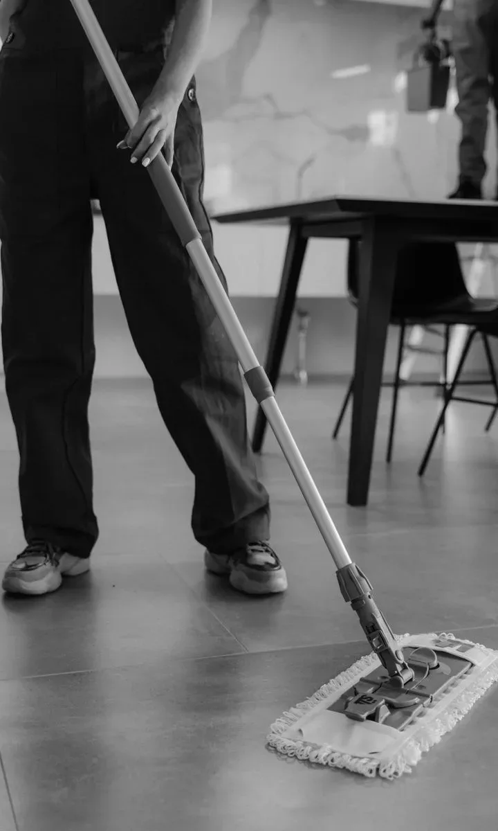 Cómo crear una estación de limpieza compacta sin ocupar espacio. Persona usando una fregona compacta para limpiar el suelo de una cocina pequeña.