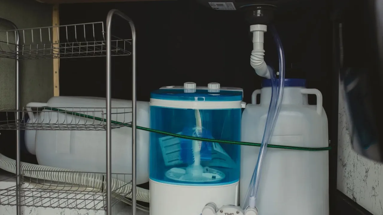 Cestas de plástico transparente apilables debajo del lavabo del baño, con productos de limpieza ordenados y visibles.