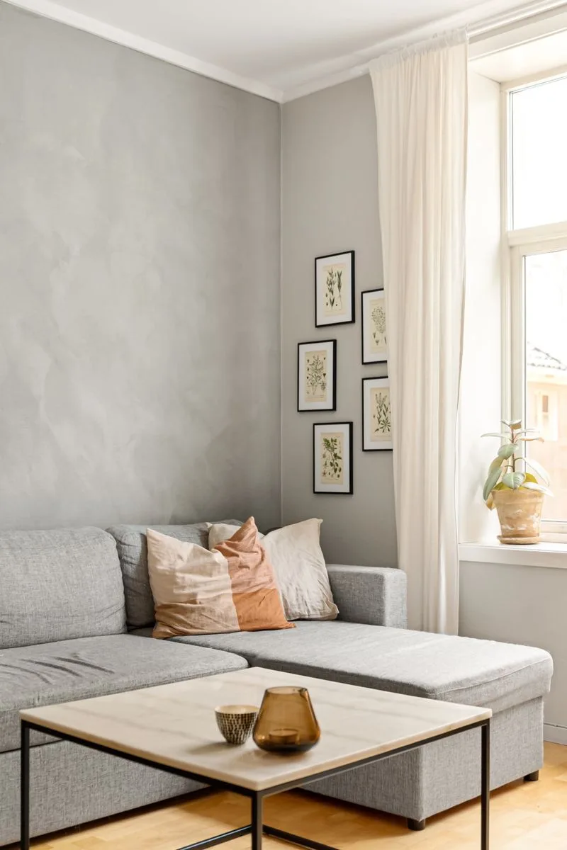 Cómo evitar que tu casa parezca desordenada y sucia Sala de estar minimalista y ordenada con muebles sencillos y luz natural, representando un hogar limpio y sin desorden.