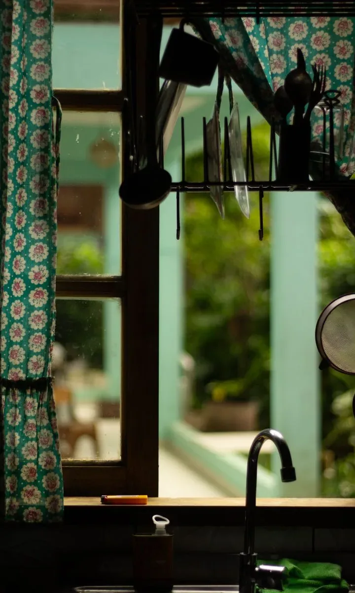 Mujer abriendo la ventana de la cocina para ventilar y eliminar malos olores