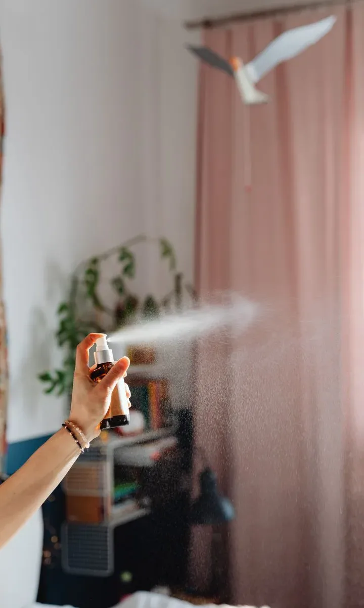 Una persona rociando insecticida en una esquina de la cocina, ilustrando las soluciones para combatir cucarachas pequeñas.