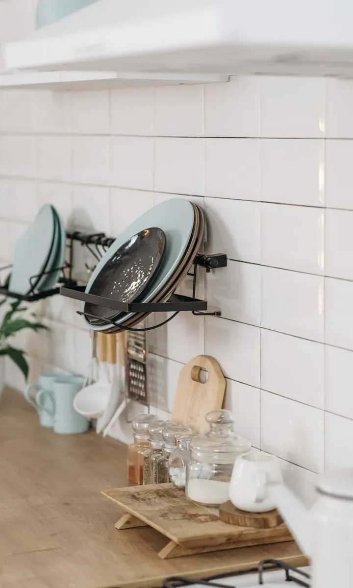 Cómo evitar que tu casa parezca desordenada y sucia Encimera de cocina organizada con utensilios y frutas en recipientes, ilustrando una cocina limpia y funcional.